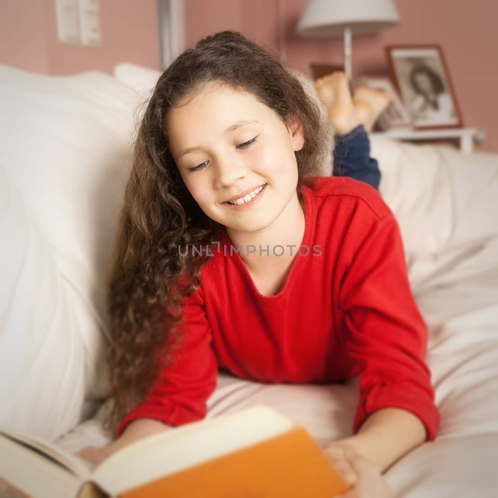 An image of a girl with a book on the sofa