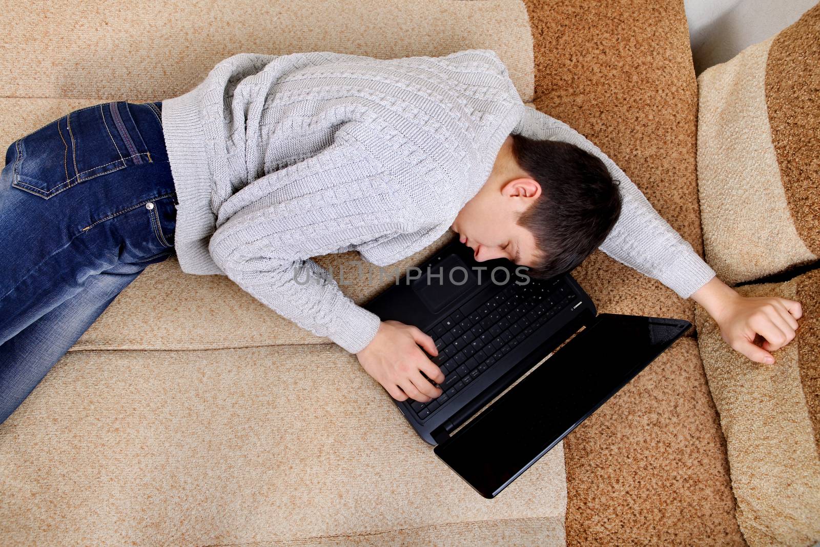 Tired Teenager falling asleep with Laptop on Sofa