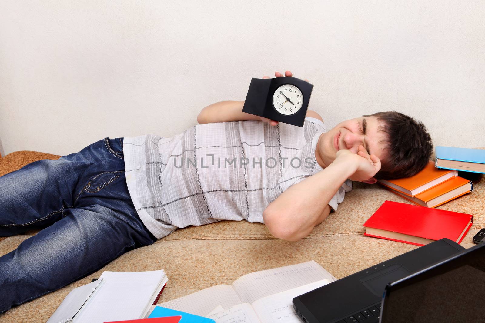 Tired Teenager on the Sofa holding the Clock
