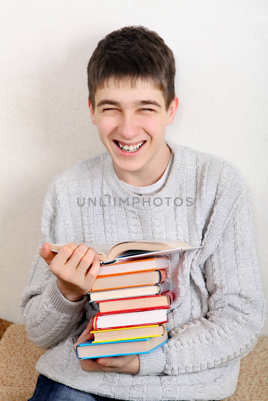 Cheerful Teenager reads a Books on the Sofa at the Home