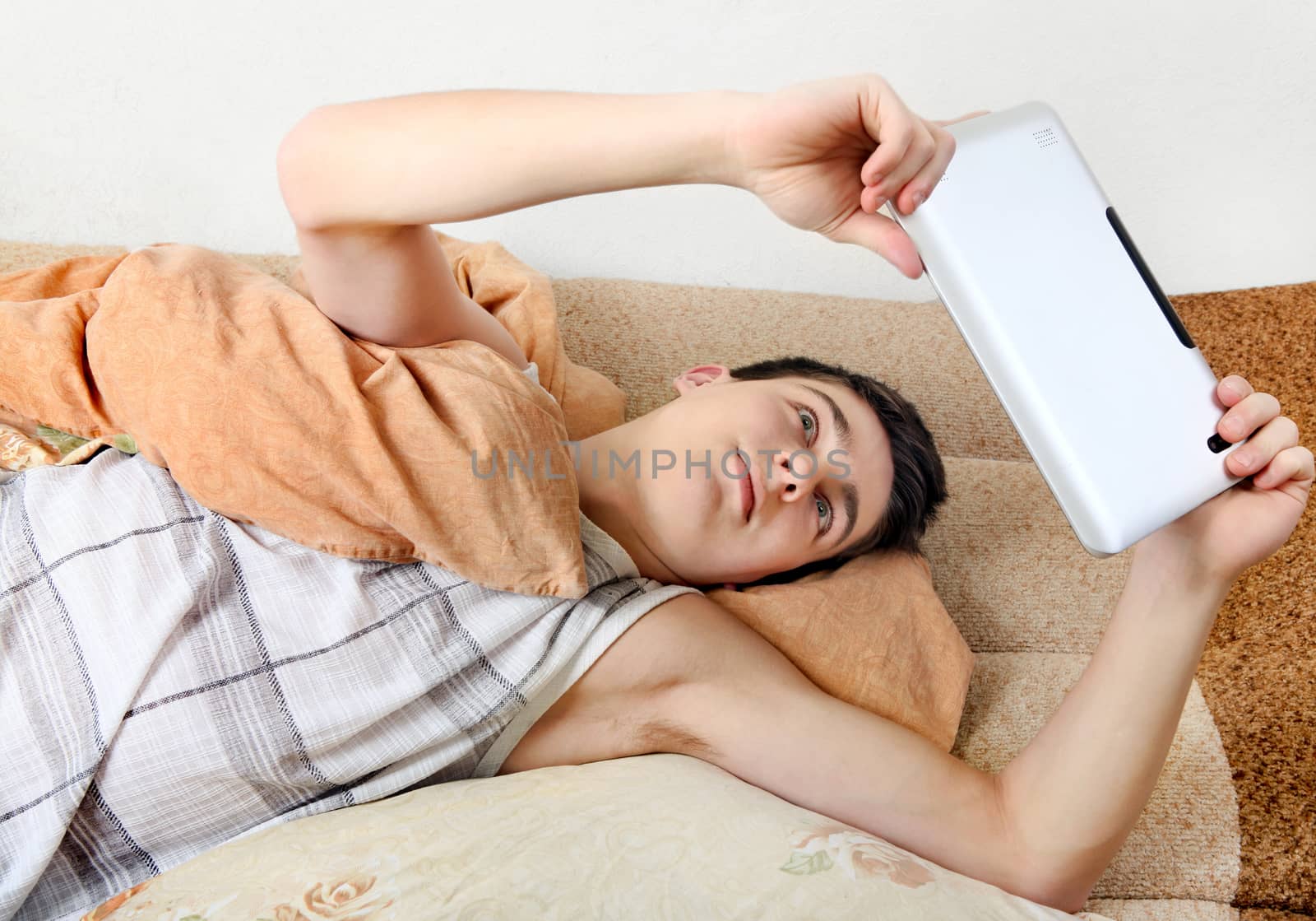 Upper view of Teenager using the Tablet Computer on the Sofa at the Home