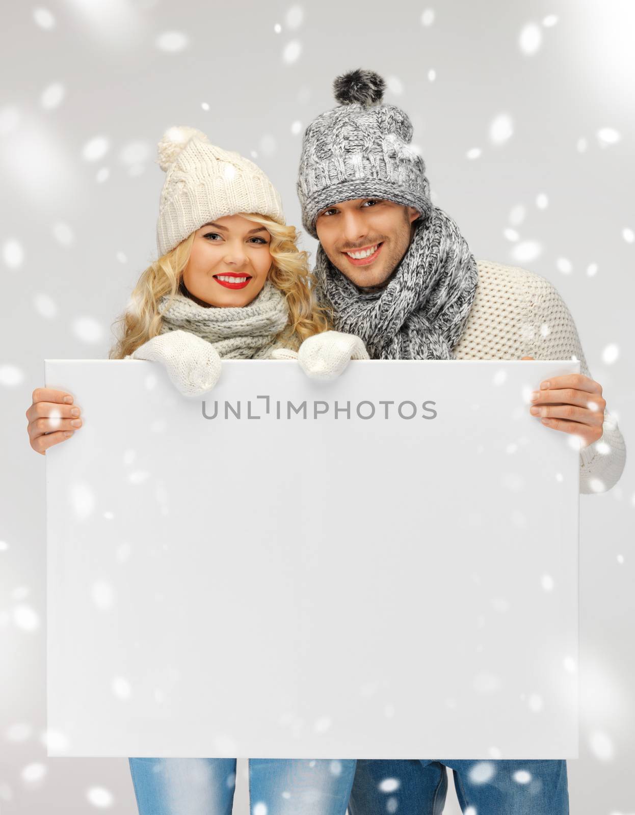 couple in a winter clothes holding blank board by dolgachov