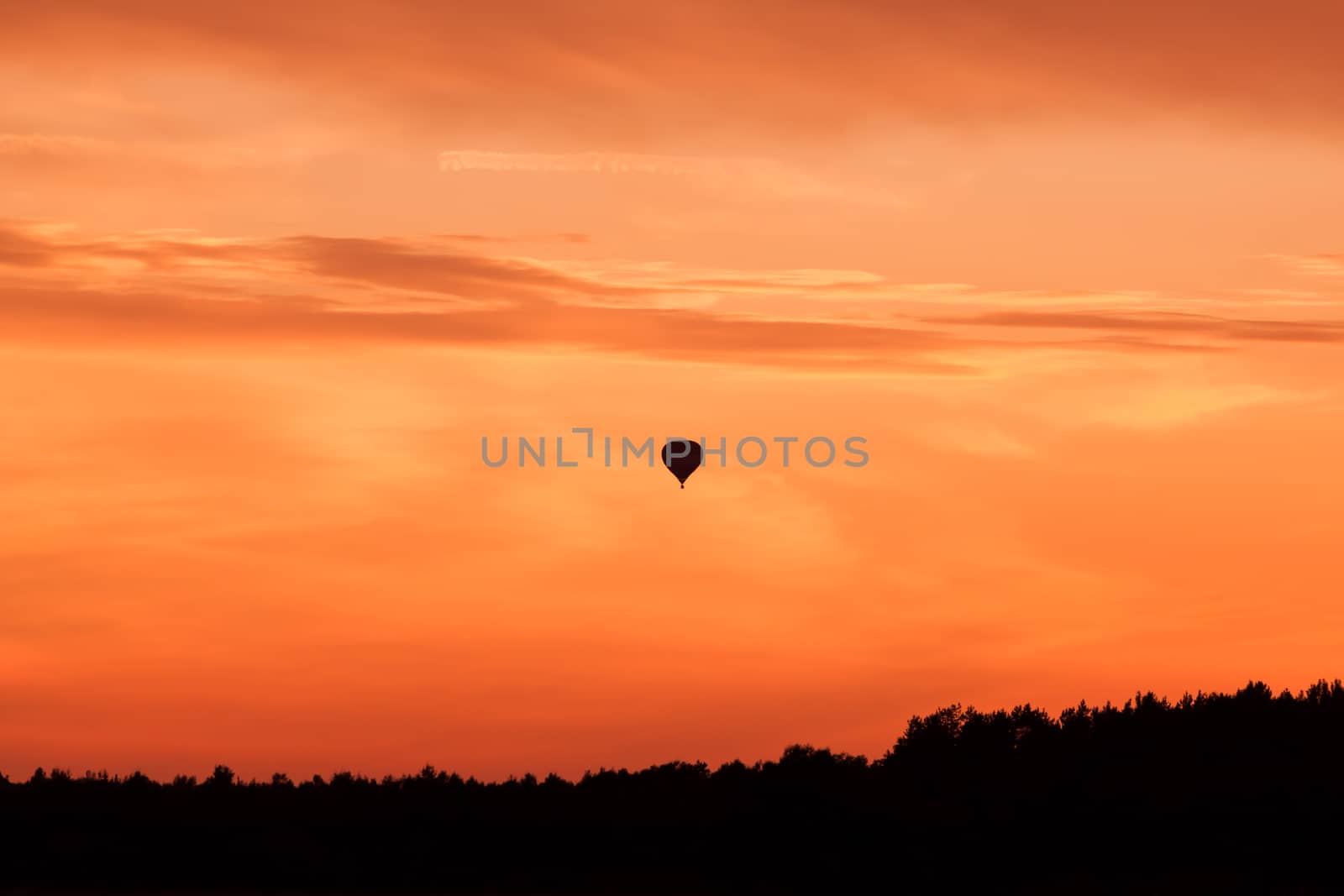 Hot air balloon flying at orange sunset sky