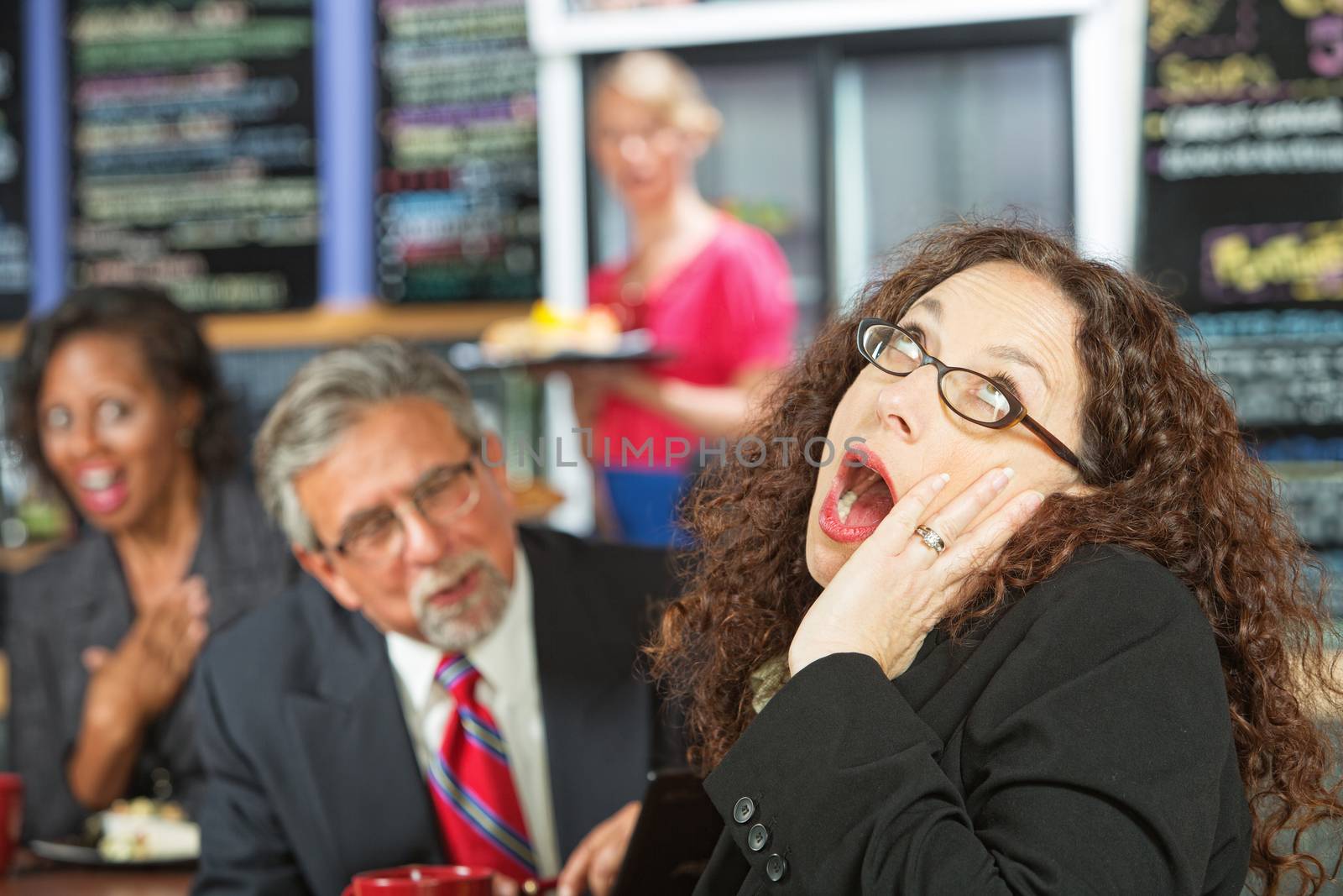 Business woman yawning as man talks to her during lunch
