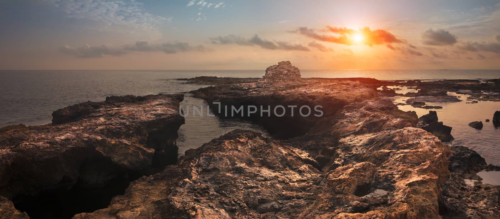 Sunset over the Sea and Rocky Coast with Ancient Ruins by Kayco