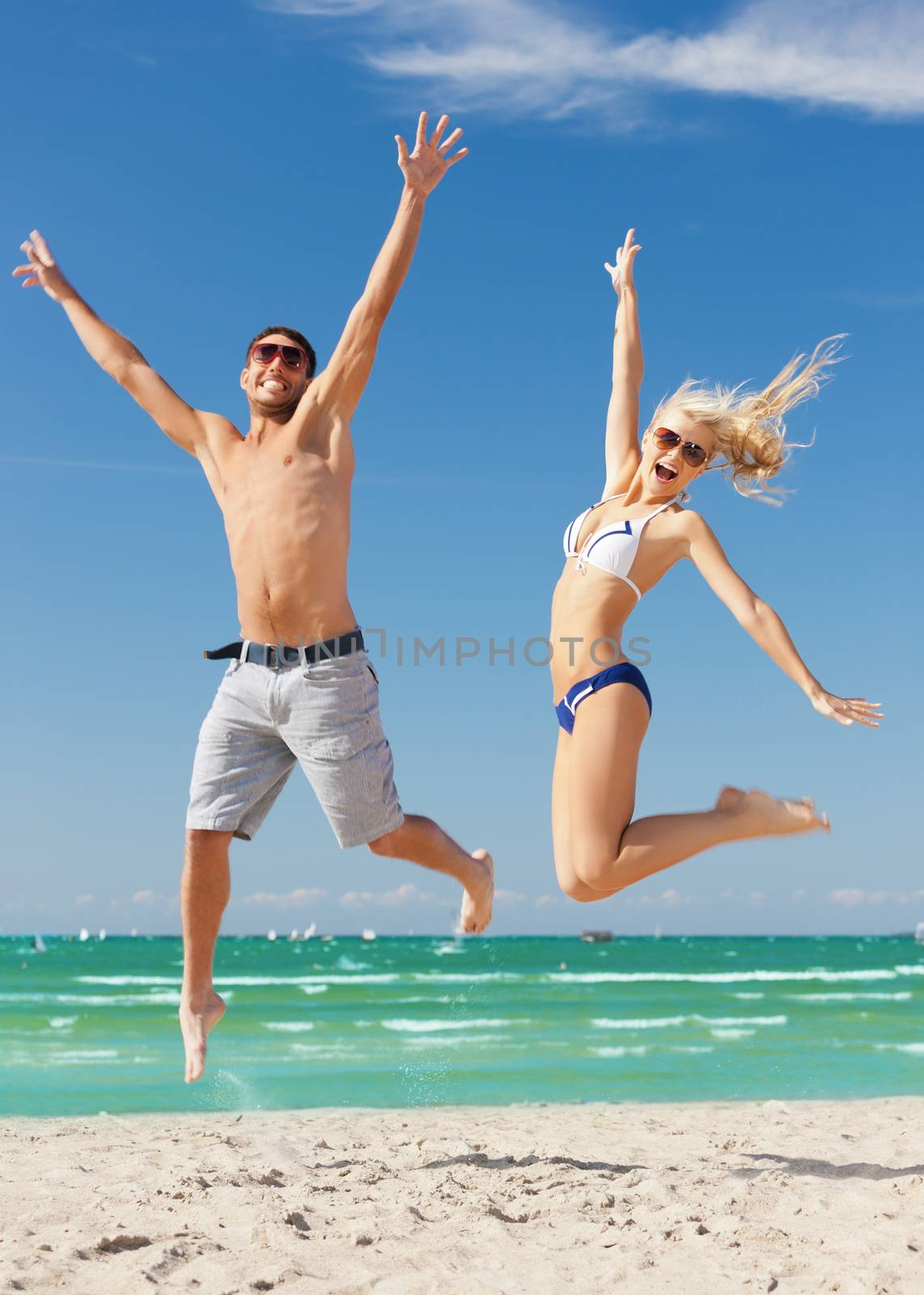 picture of happy couple jumping on the beach