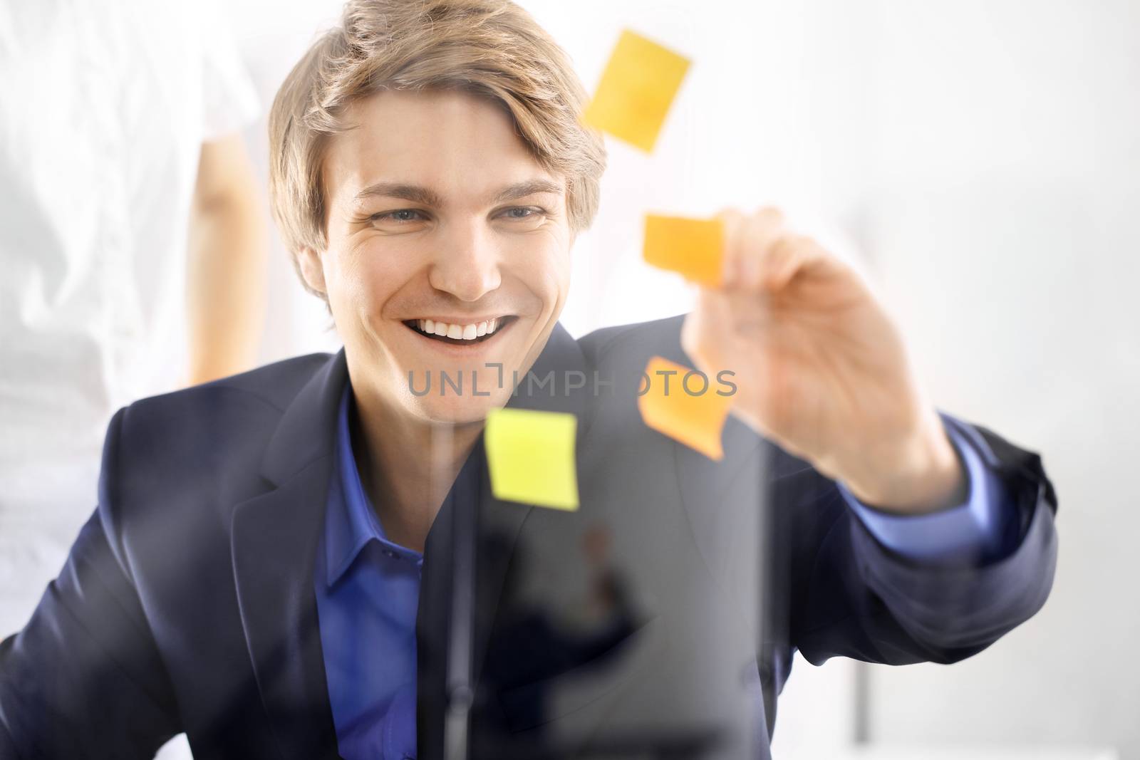 Young, handsome man of success in the office room glued yellow notes