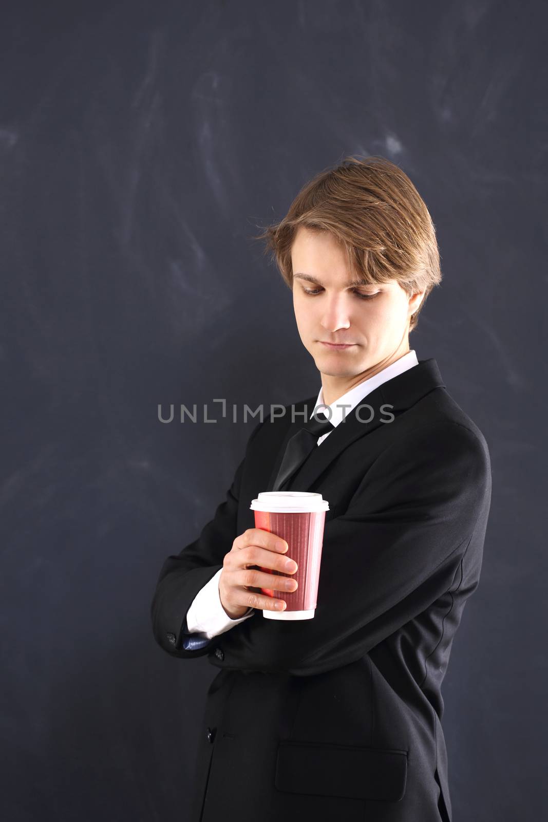 Portrait of a young, handsome man standing against the background of blackboard