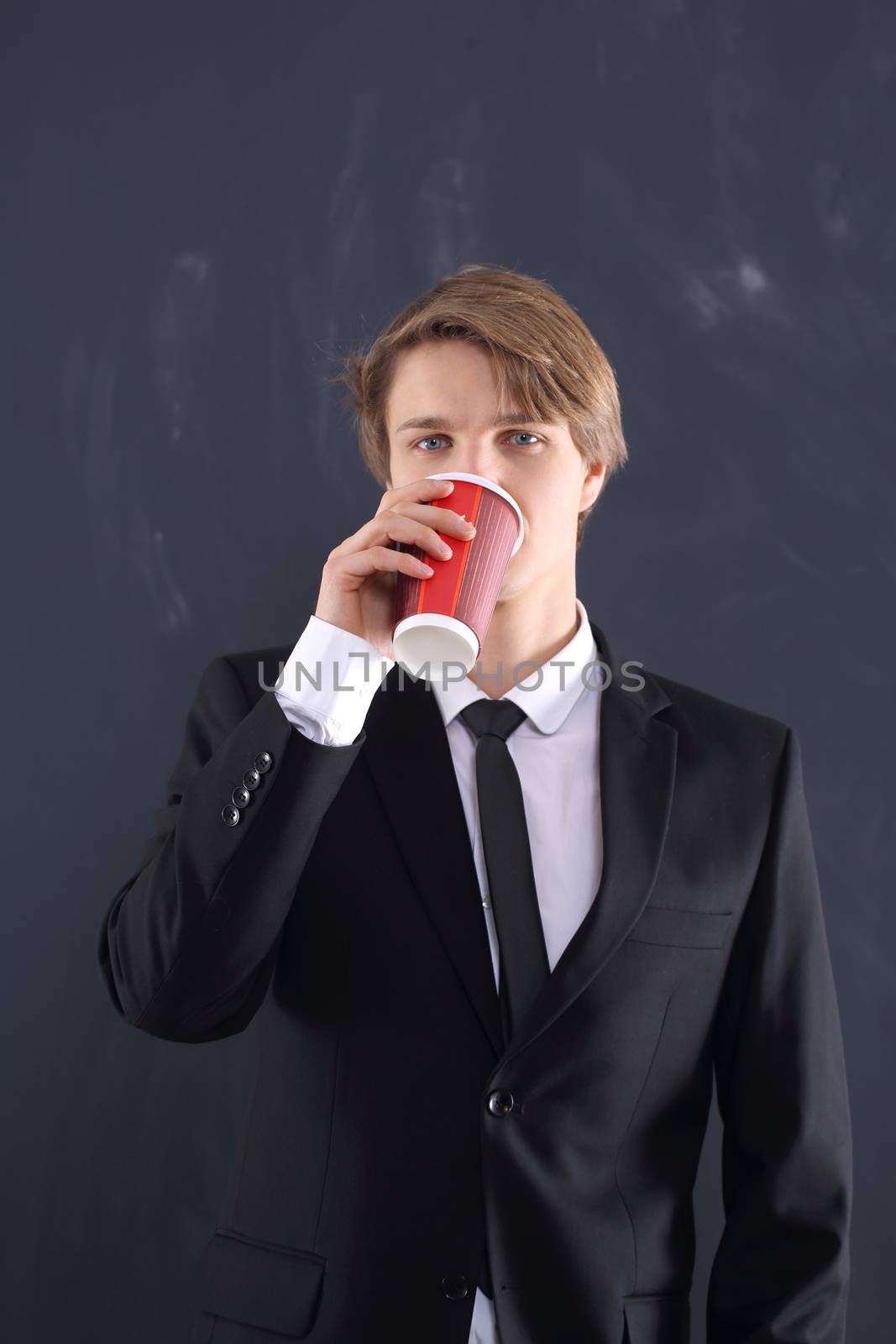 Portrait of a young, handsome man standing against the background of blackboard