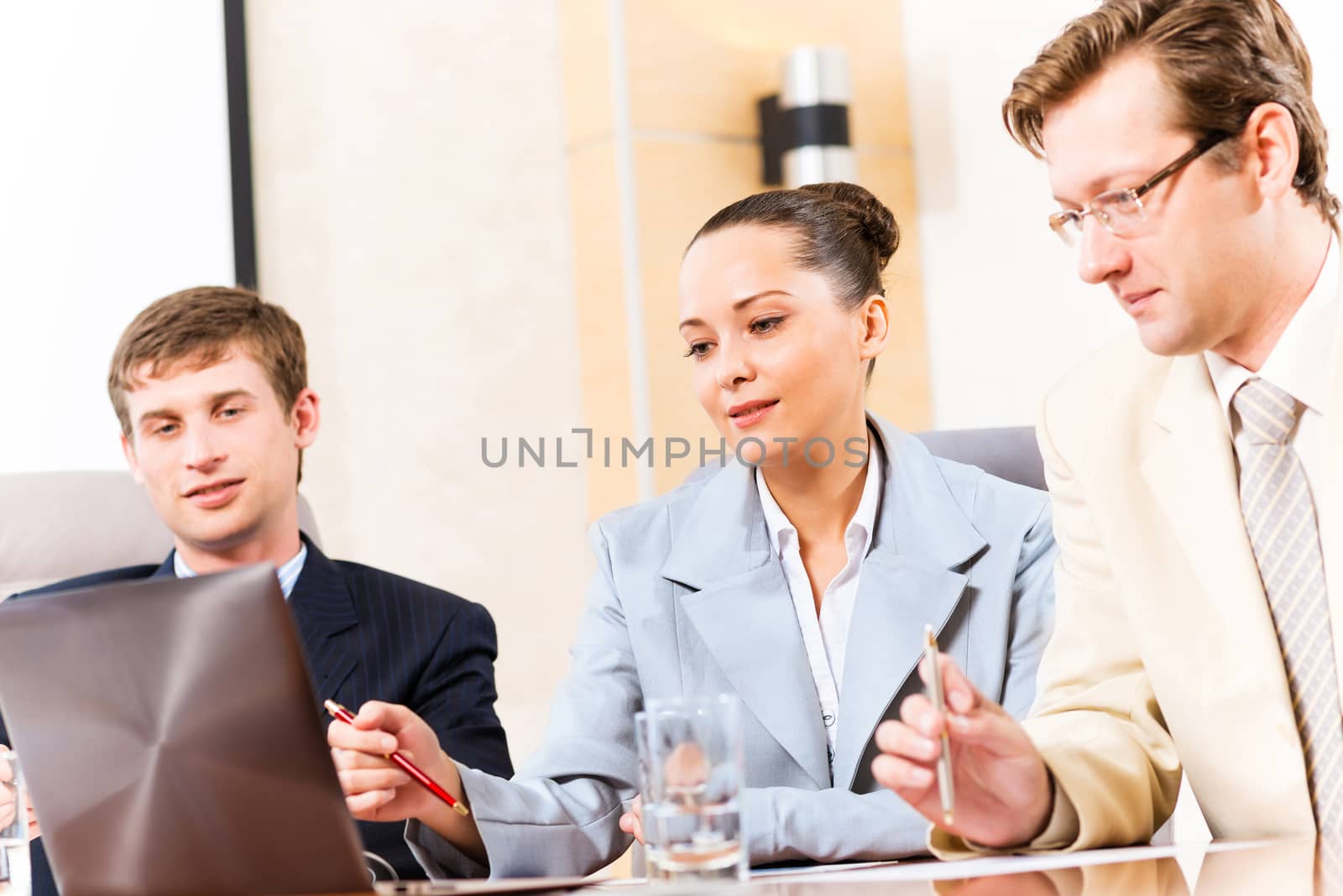 Business people talking, sitting at the table, watching the presentation on a laptop