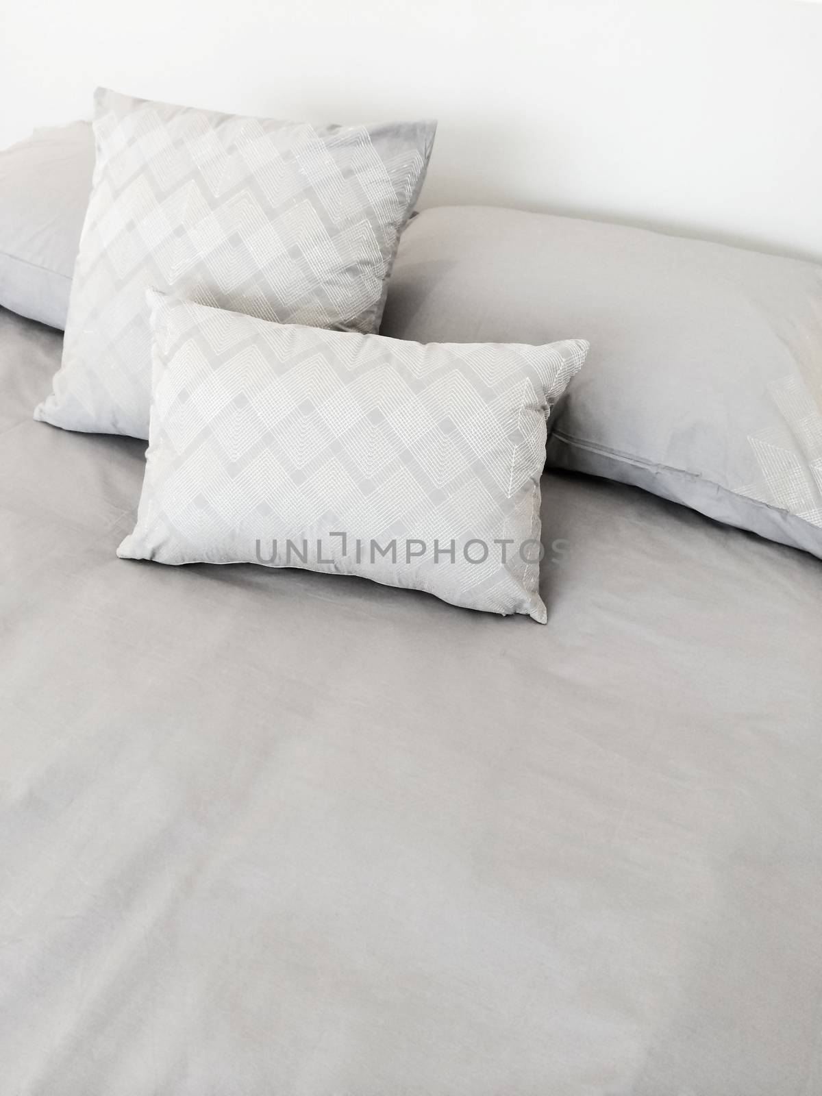 Bed with grey bed linen and pillows.