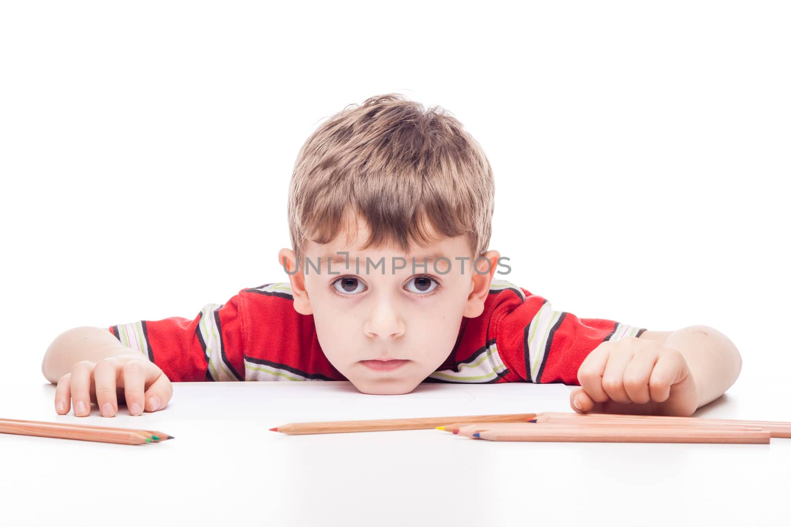 young boy with drawig pencil at white table