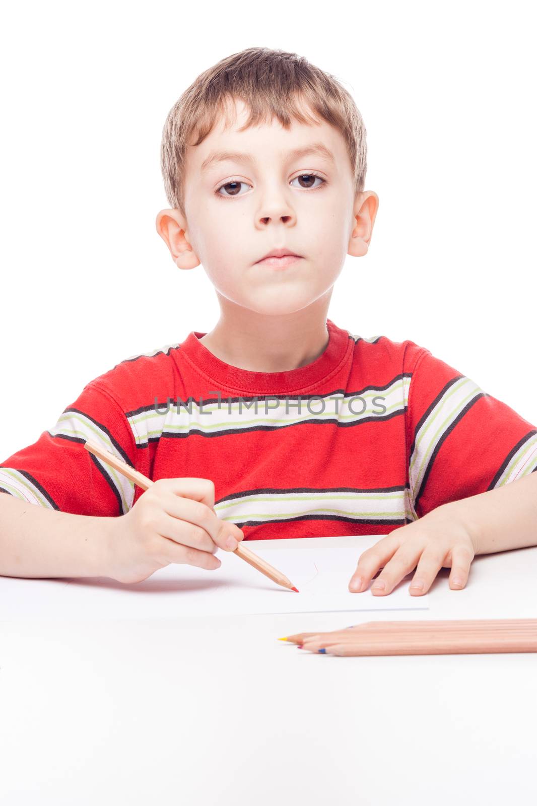 young boy with drawig pencil at white table