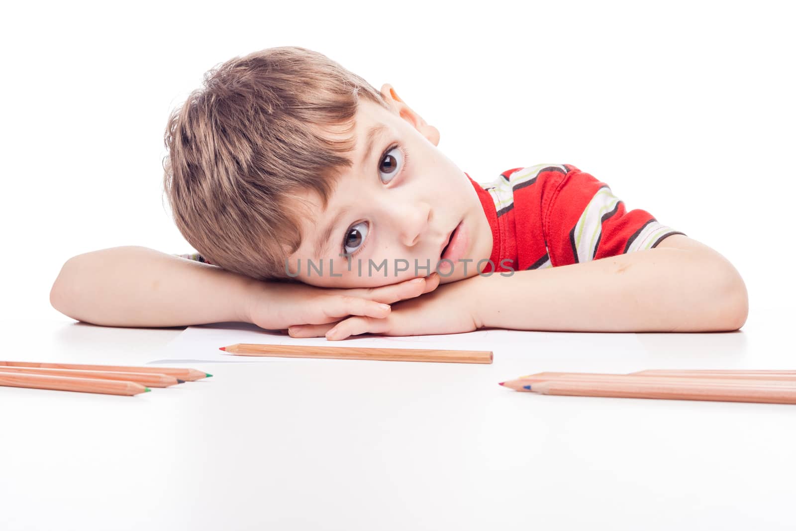 young boy with drawig pencil at white table