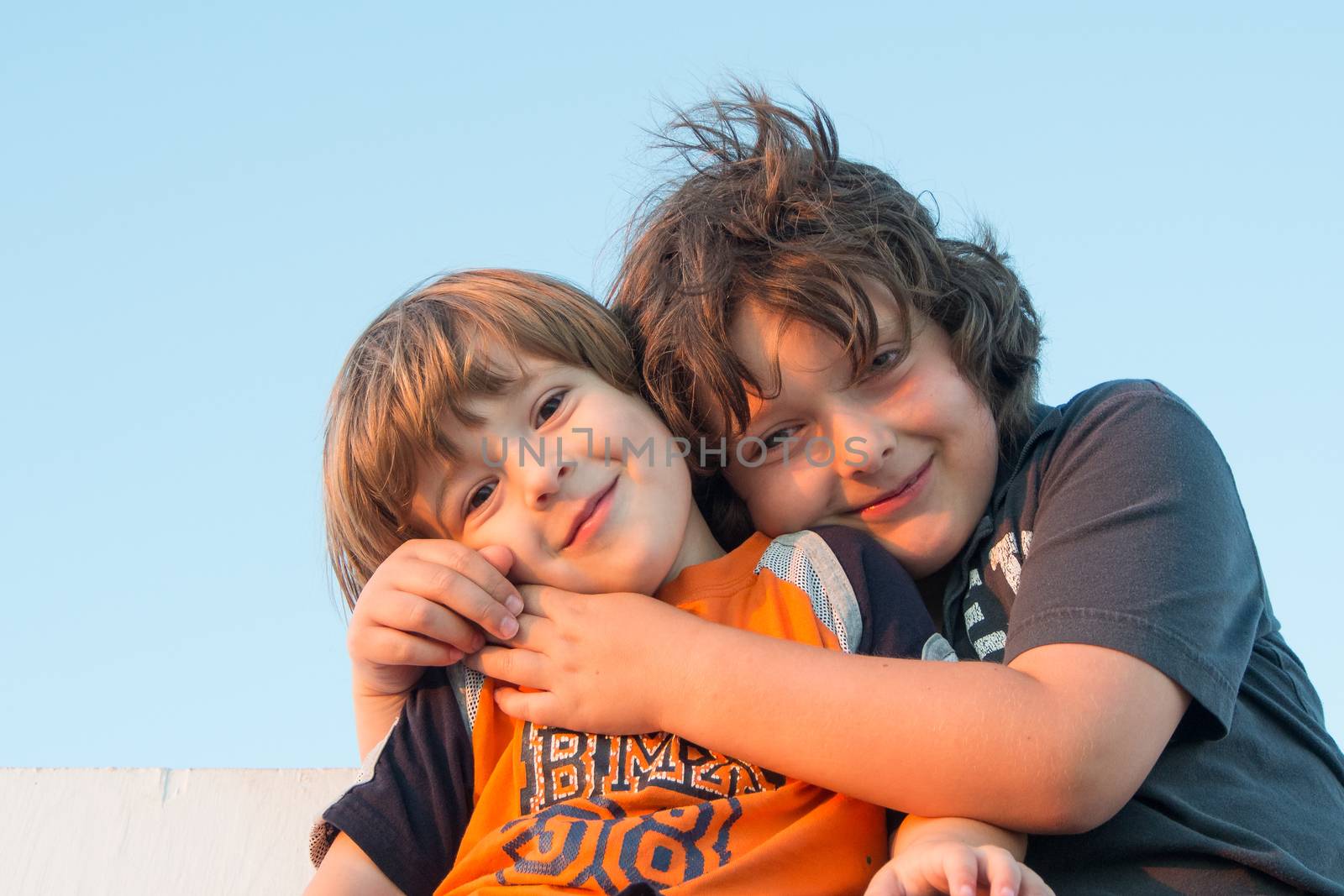 Brothers hugging at sunset by Talanis