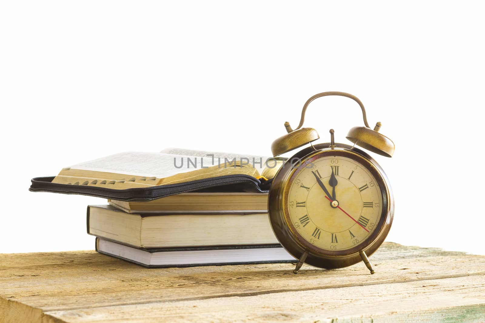 open Holy Bible with clock on wood with white background