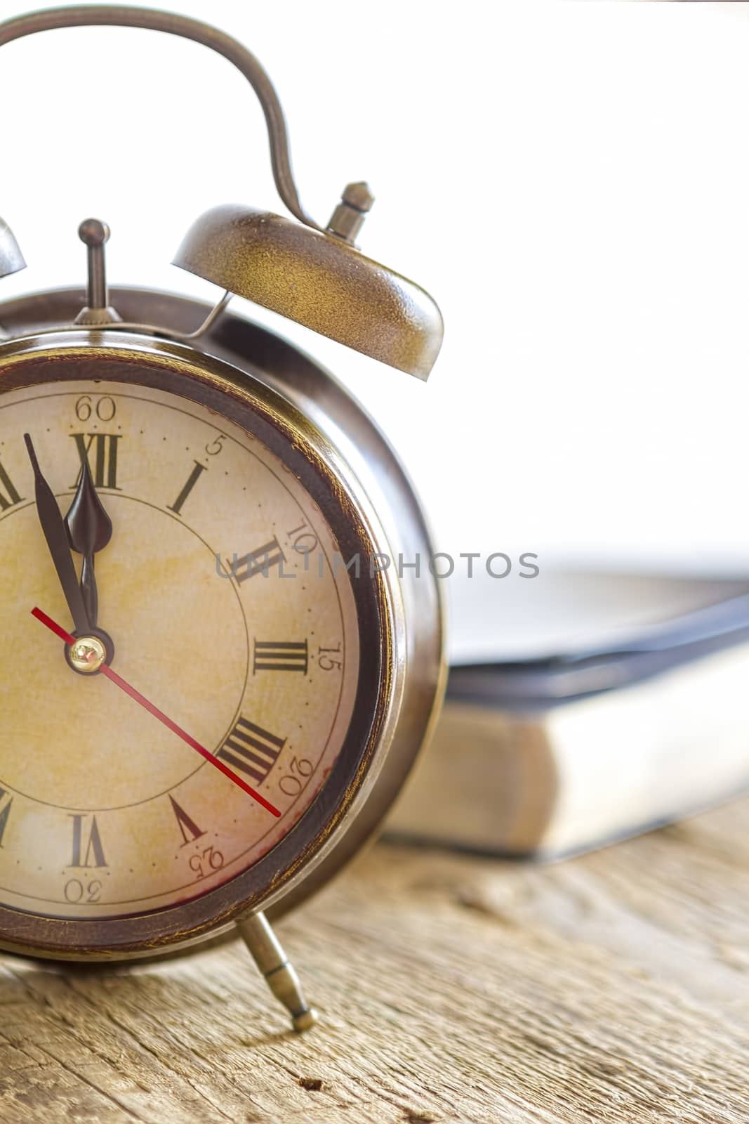 Clock and Bible on wood. Concept of clock showing a few minutes to twelve o'clock. Focus on the clock.