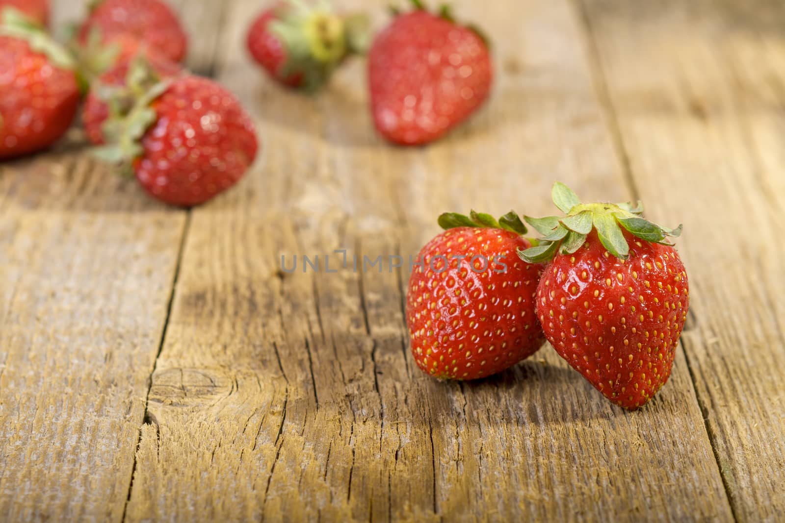 fresh strawberries on wooden table. focus on first two strawberries