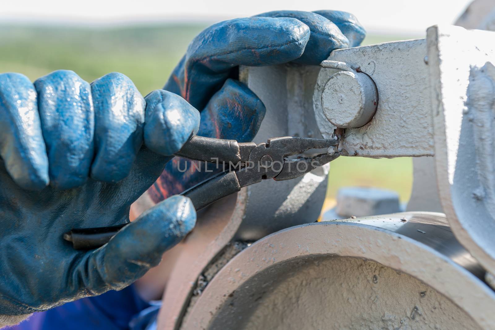 repair oil equipment. Hand in gloves blue with pliers