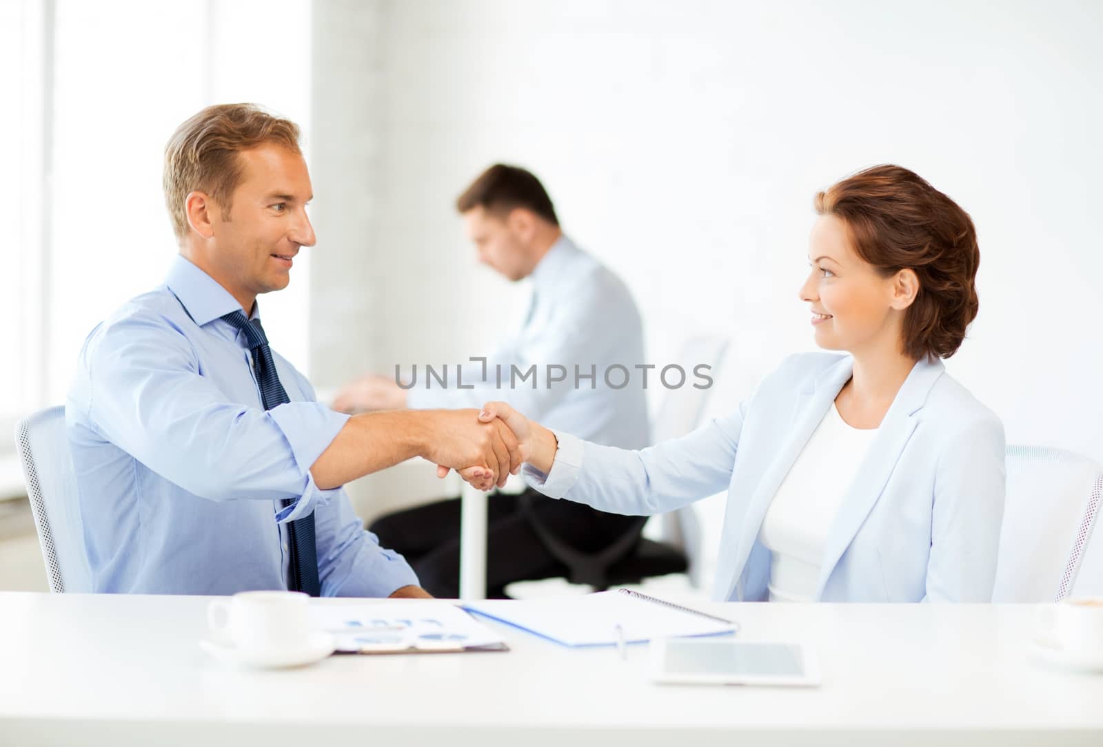 man and woman shaking hands in office by dolgachov
