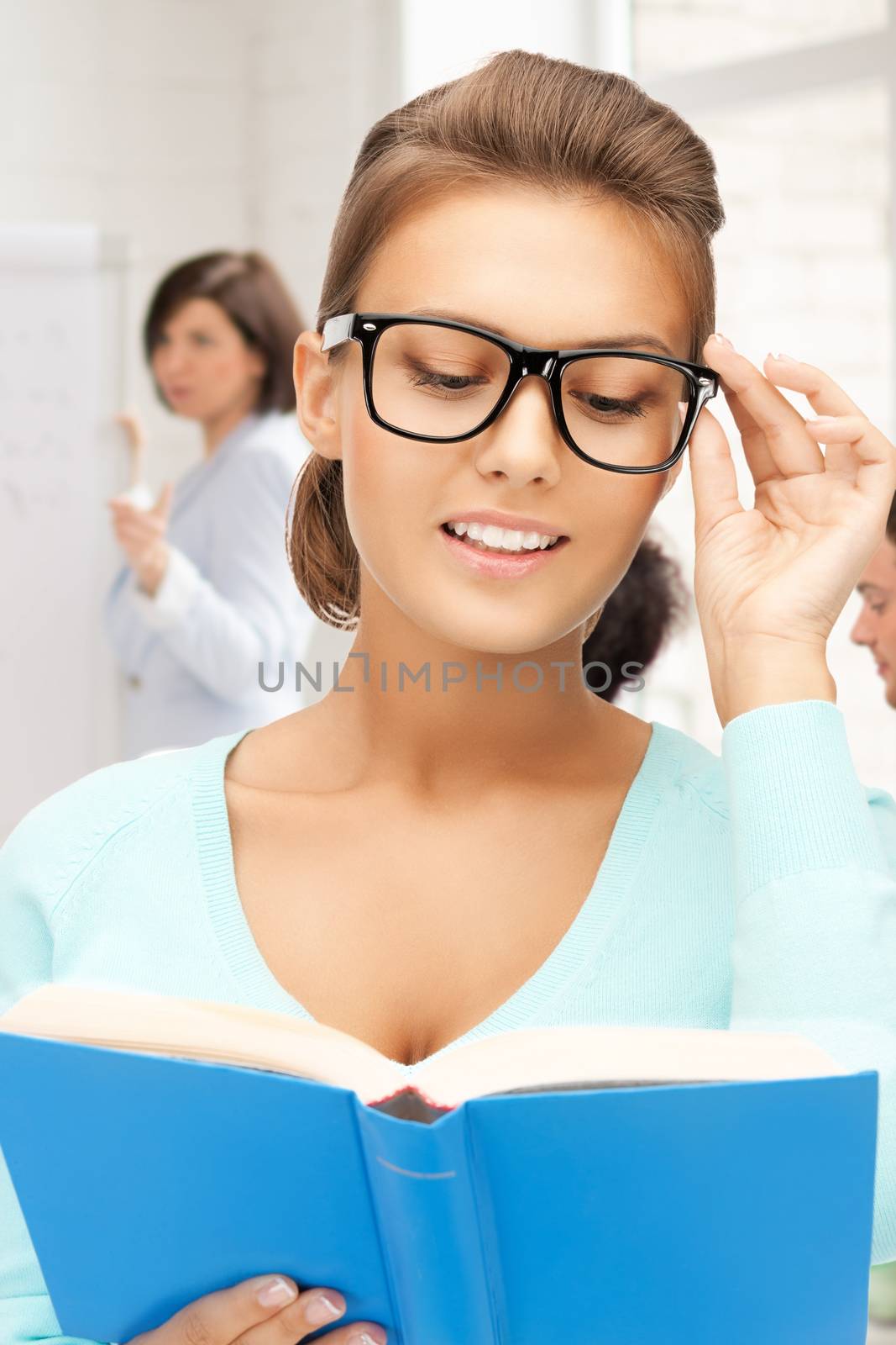 smiling student girl in glasses reading book at school