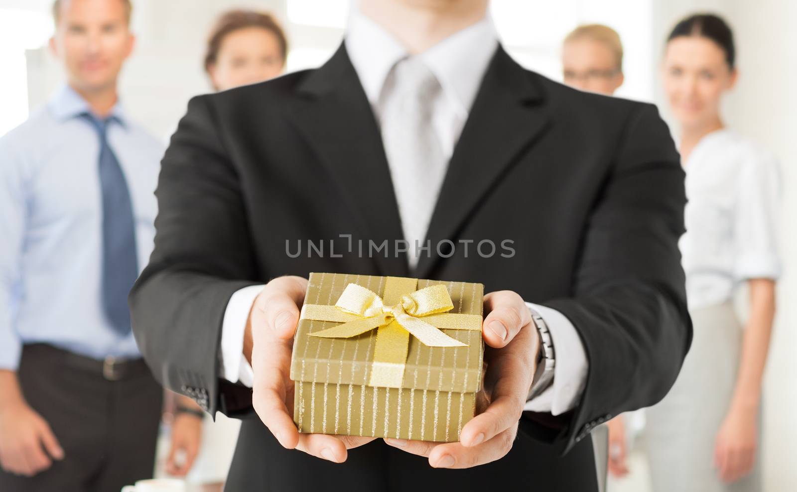 man hands holding gift box in office by dolgachov