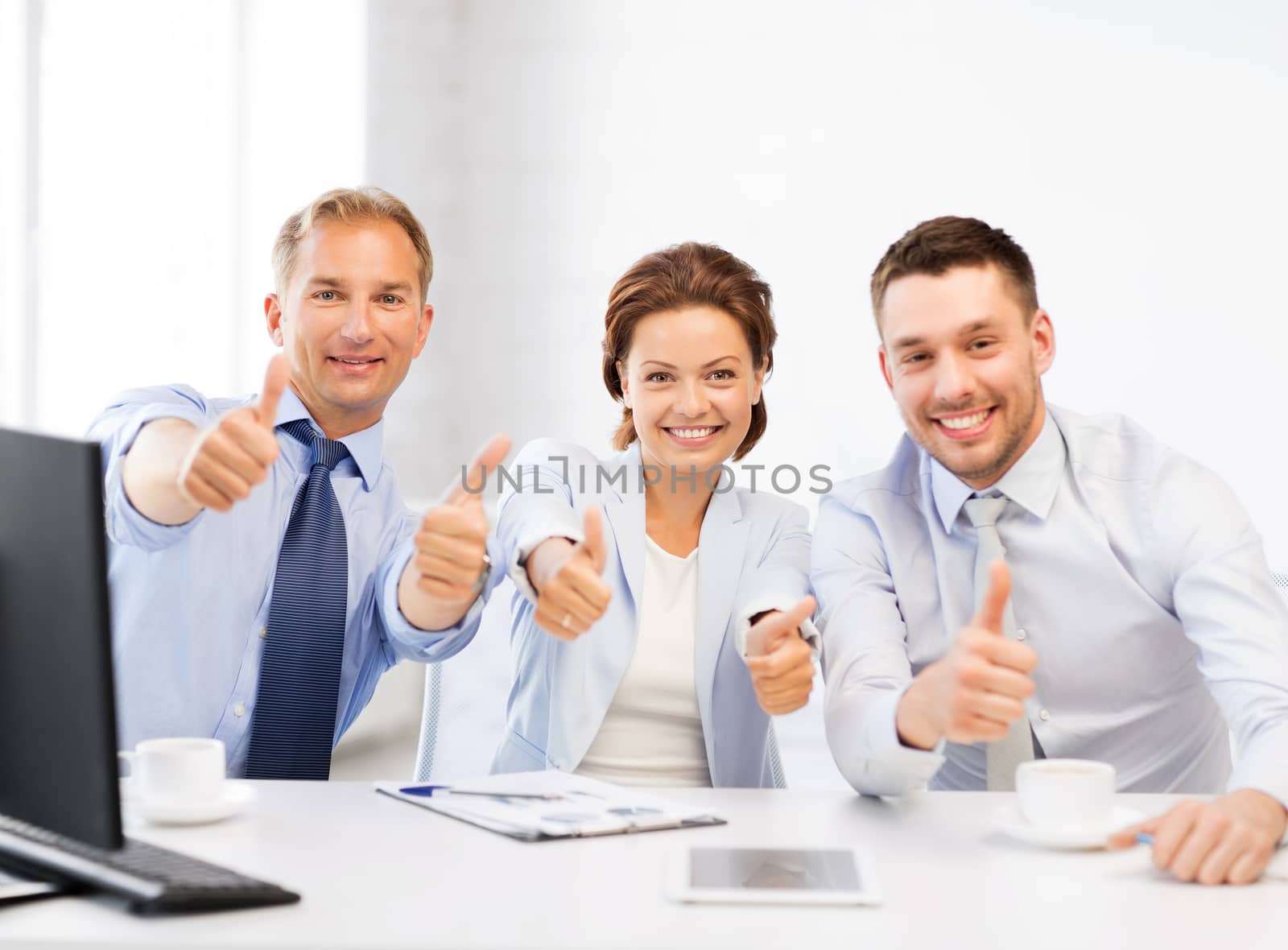 business team showing thumbs up in office by dolgachov