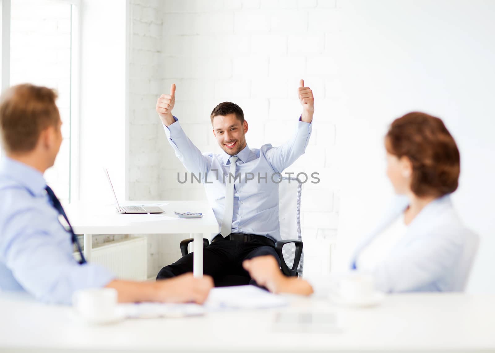 happy businessman showing thumbs up in office by dolgachov