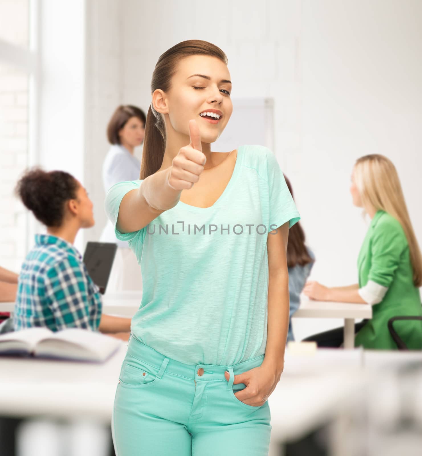 smiling girl in color t-shirt showing thumbs up at school