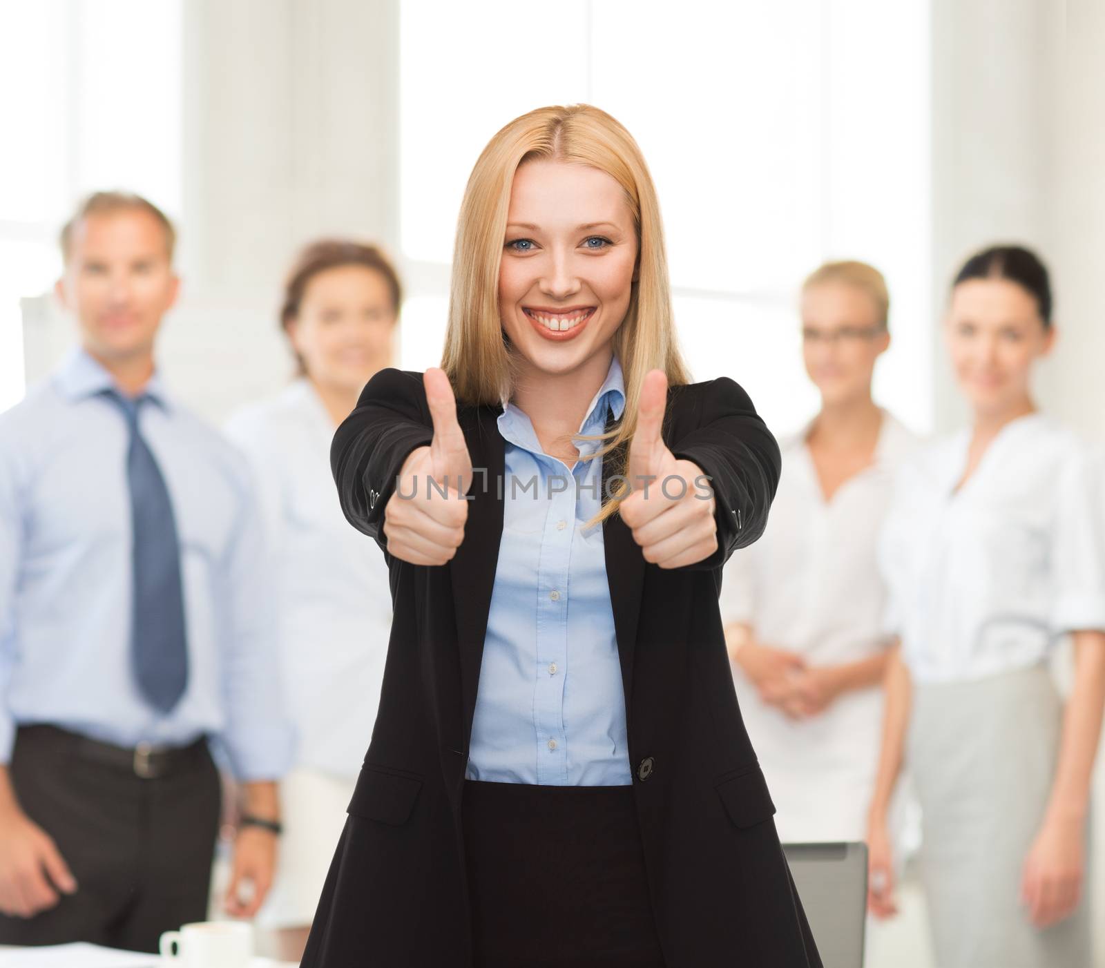 businesswoman with thumbs up in office by dolgachov
