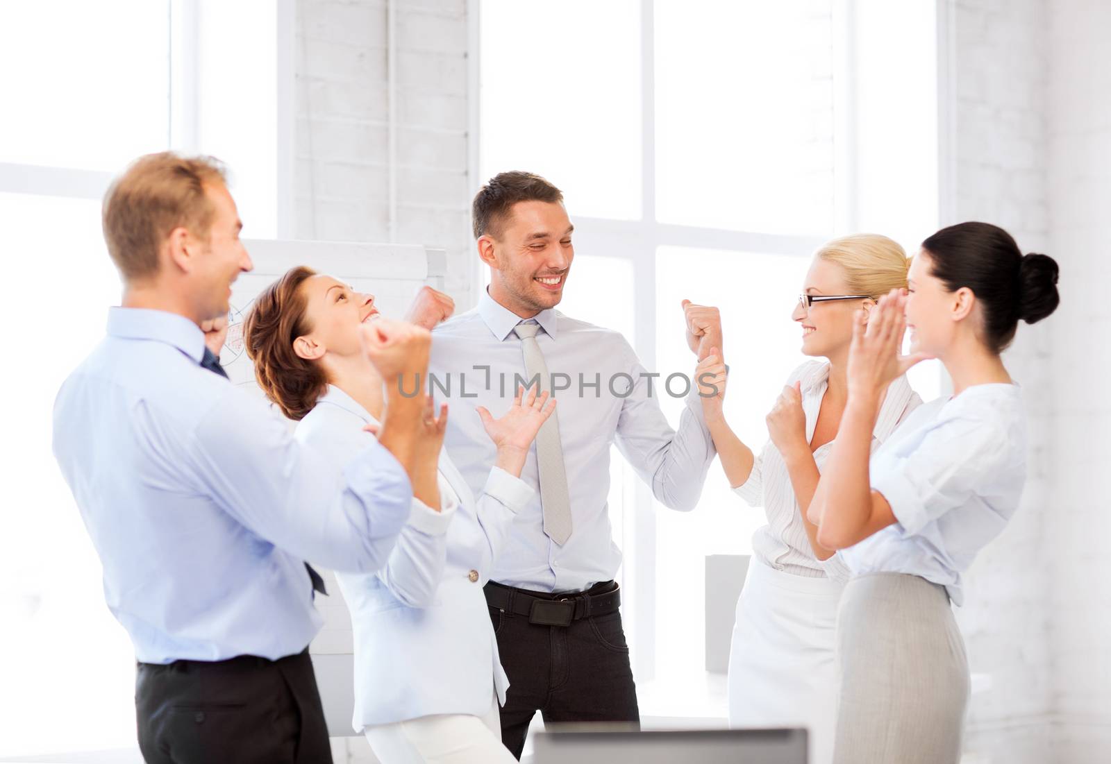 business team celebrating victory in office by dolgachov