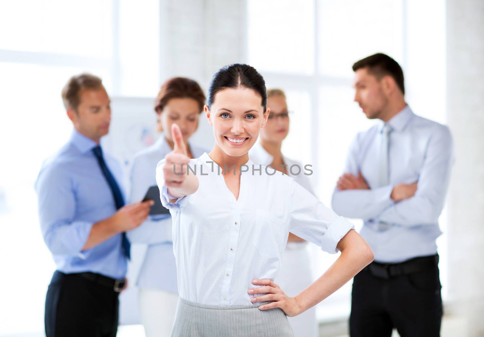 businesswoman in office showing thumbs up by dolgachov