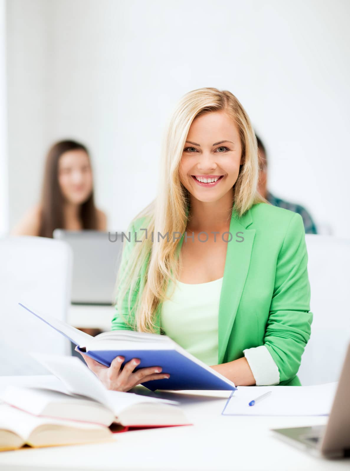 picture of smiling young woman reading book at school