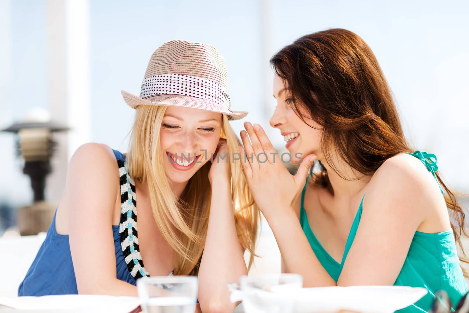 summer holidays and vacation - girls gossiping in cafe on the beach