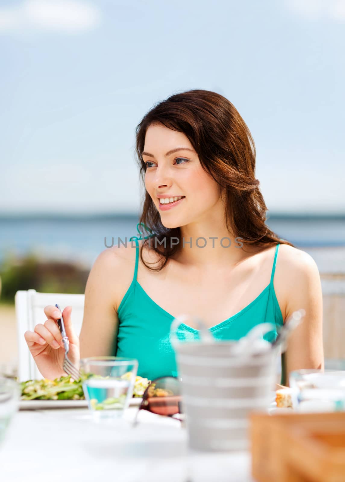 summer holidays and vacation - girl eating in cafe on the beach