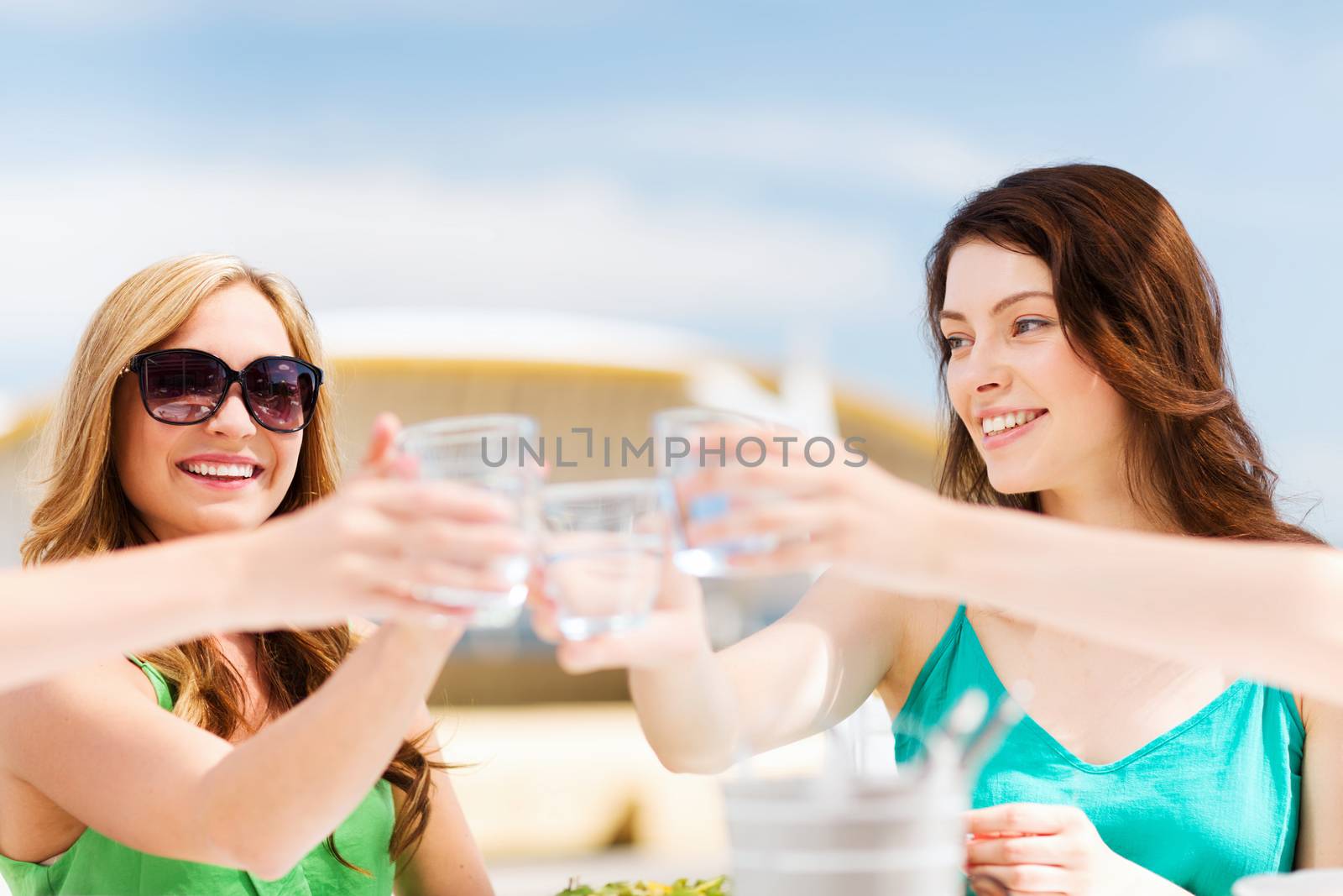 summer holidays and vacation - girls making a toast in cafe on the beach