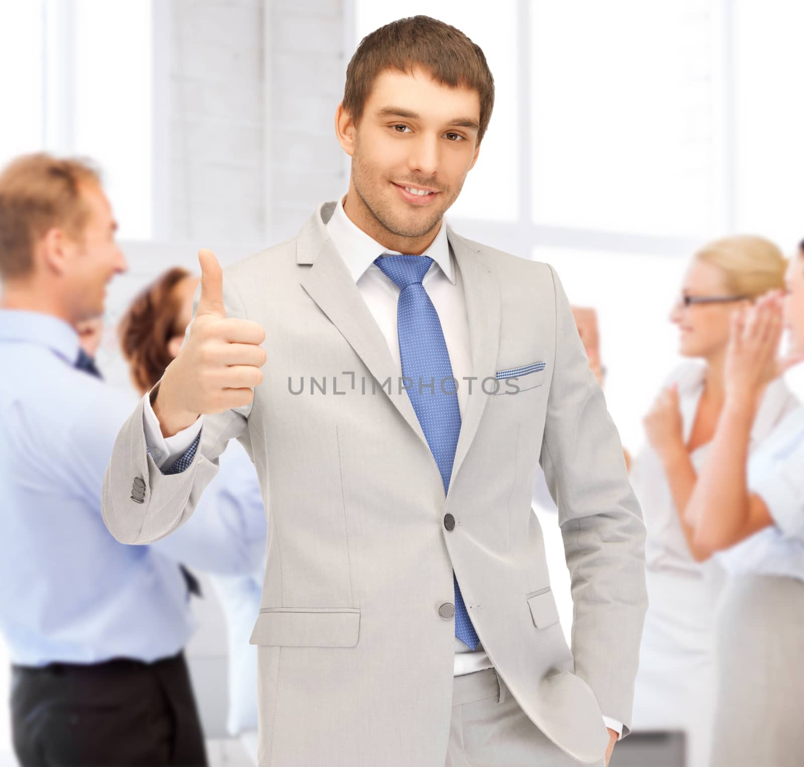 businessman showing thumbs up in office by dolgachov