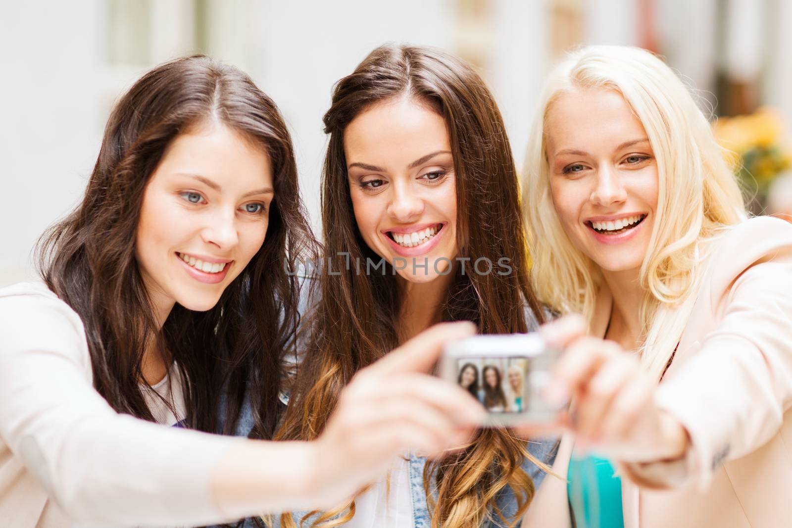holidays and tourism concept - beautiful girls taking picture in cafe in city