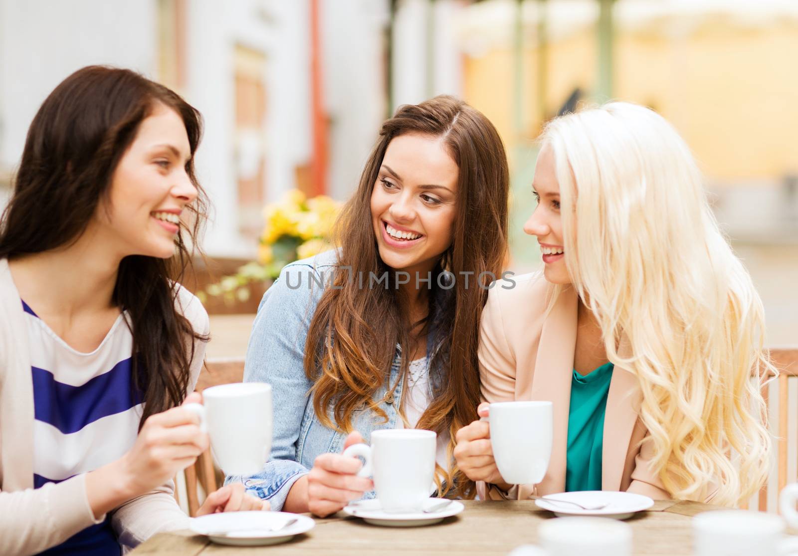 holidays and tourism concept - beautiful girls drinking coffee in cafe