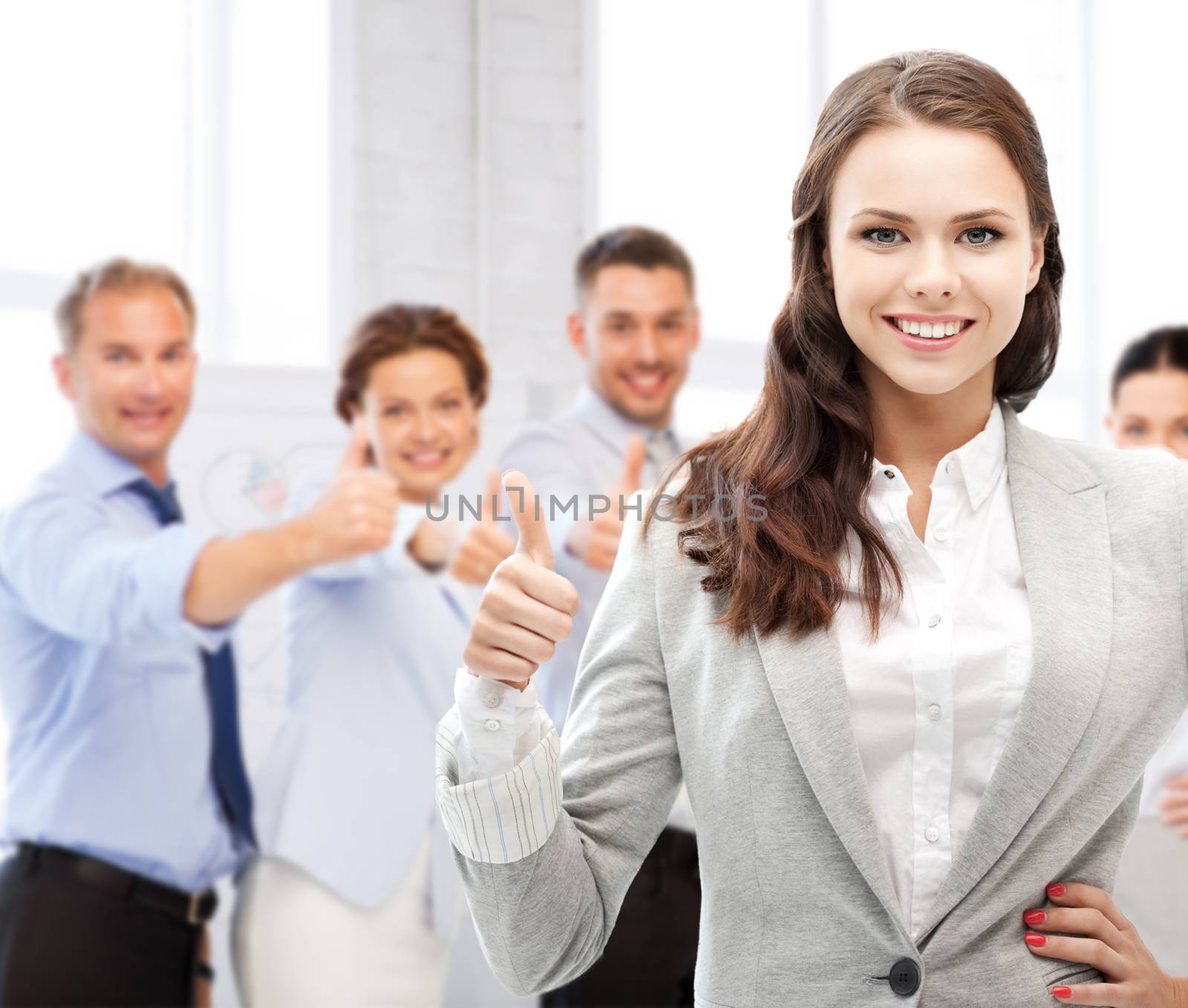 businesswoman showing thumbs up in office by dolgachov