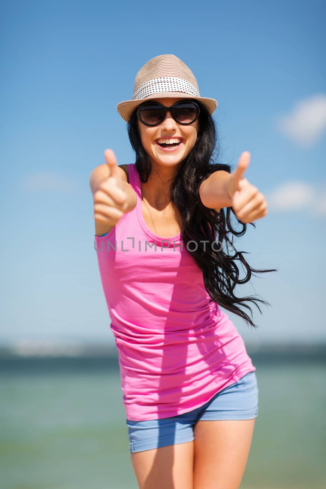 girl showing thumbs up on the beach by dolgachov