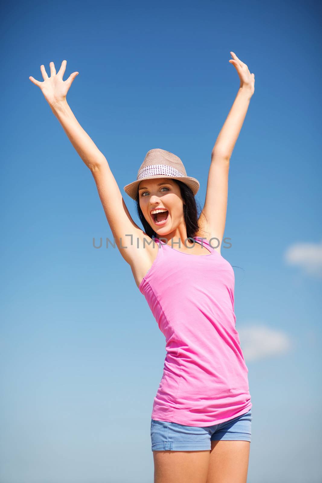 summer holidays and vacation - girl with hands up on the beach