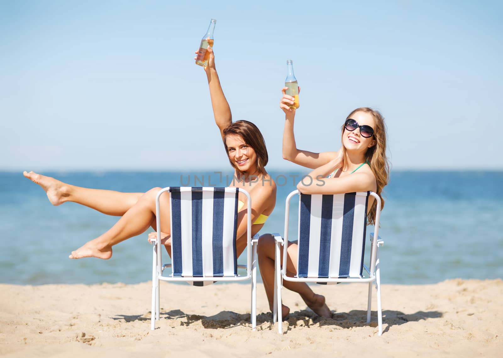 summer holidays and vacation - girls sunbathing and drinking on the beach chairs