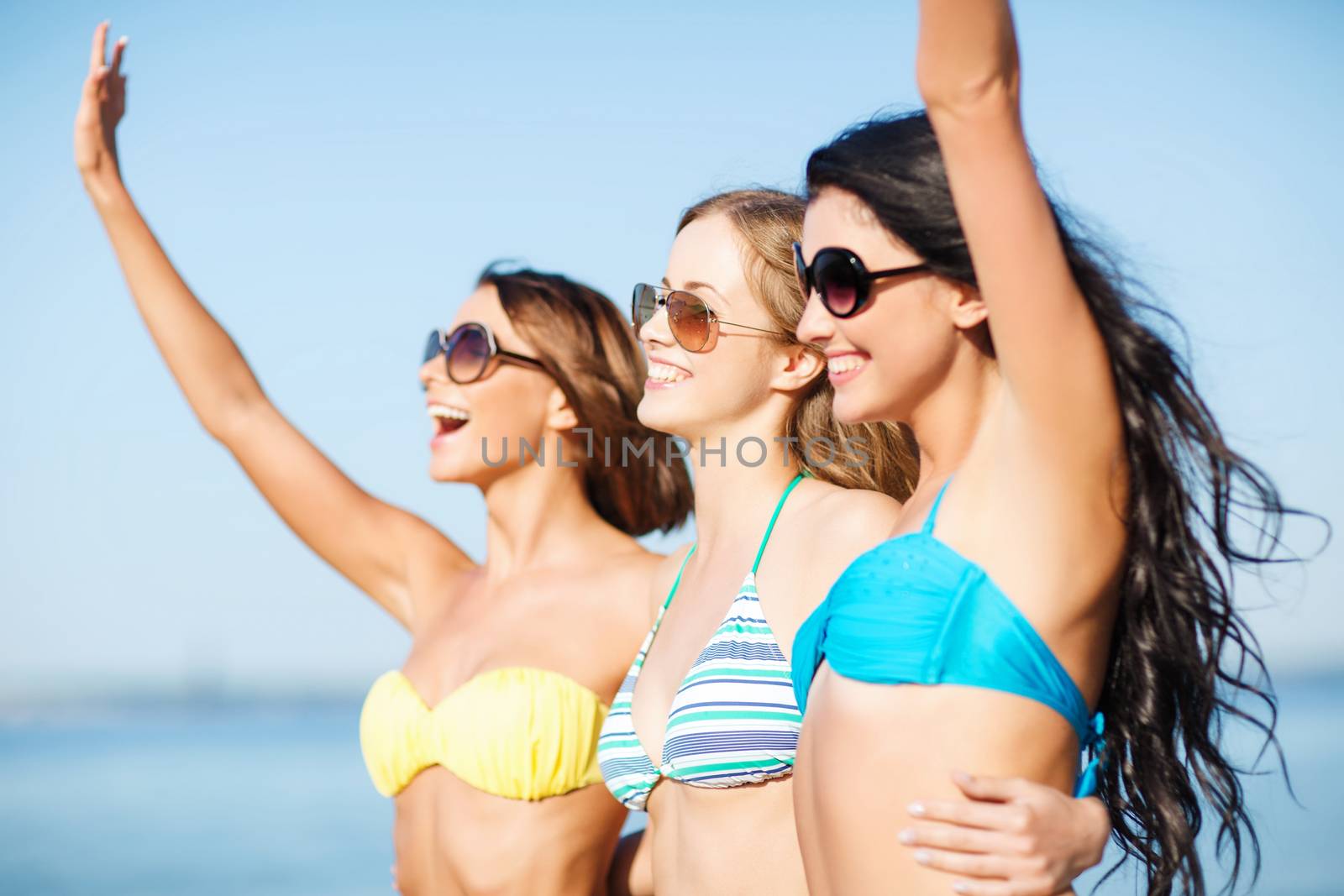 girls in bikini walking on the beach by dolgachov