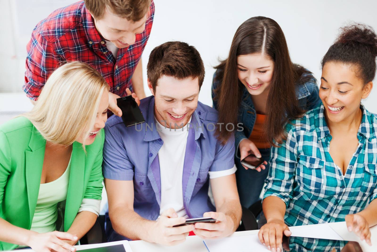 students looking into smartphone at school by dolgachov