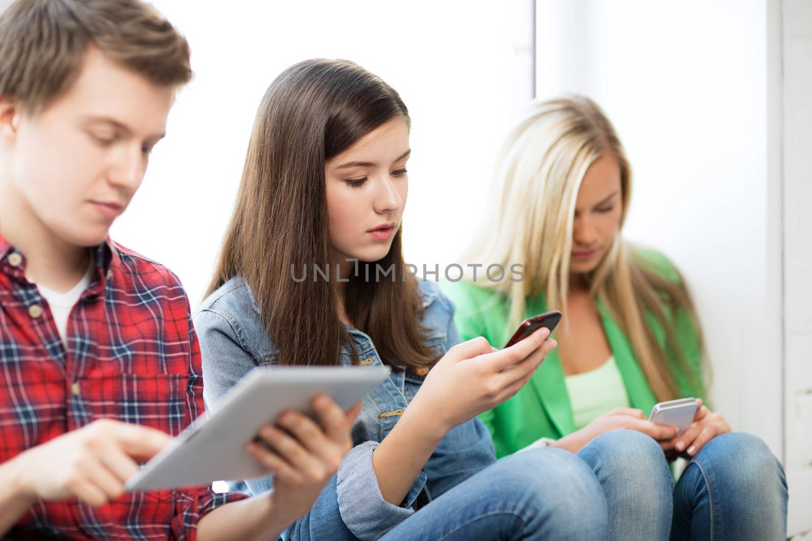 students looking into devices at school by dolgachov