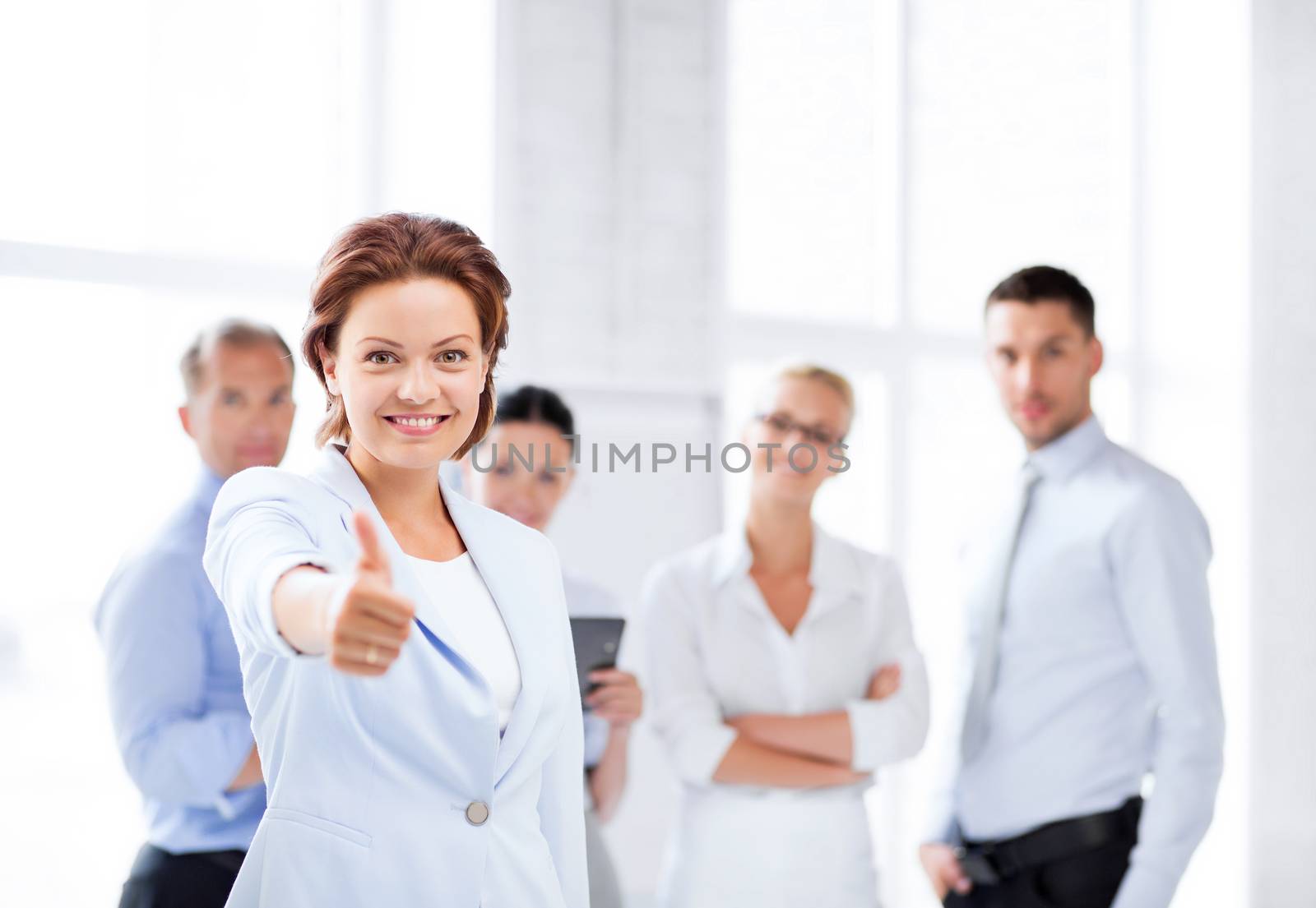 businesswoman in office showing thumbs up by dolgachov