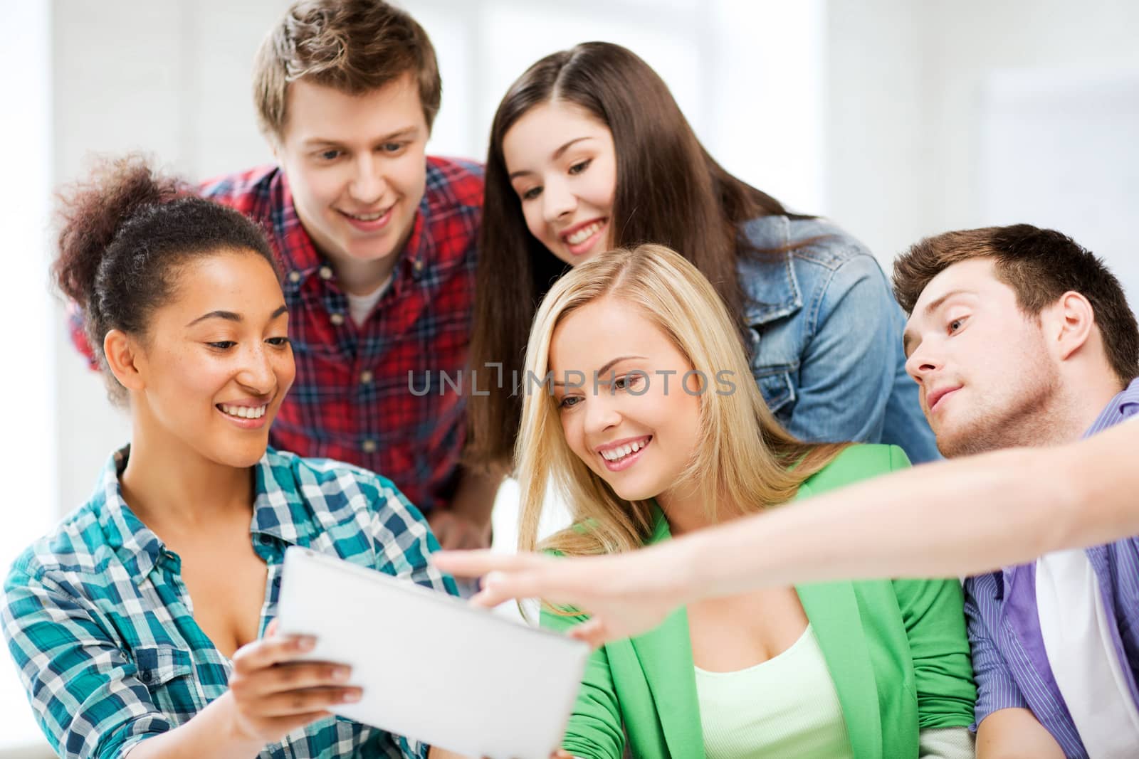 education, technology and internet concept - smiling students looking at tablet pc at school