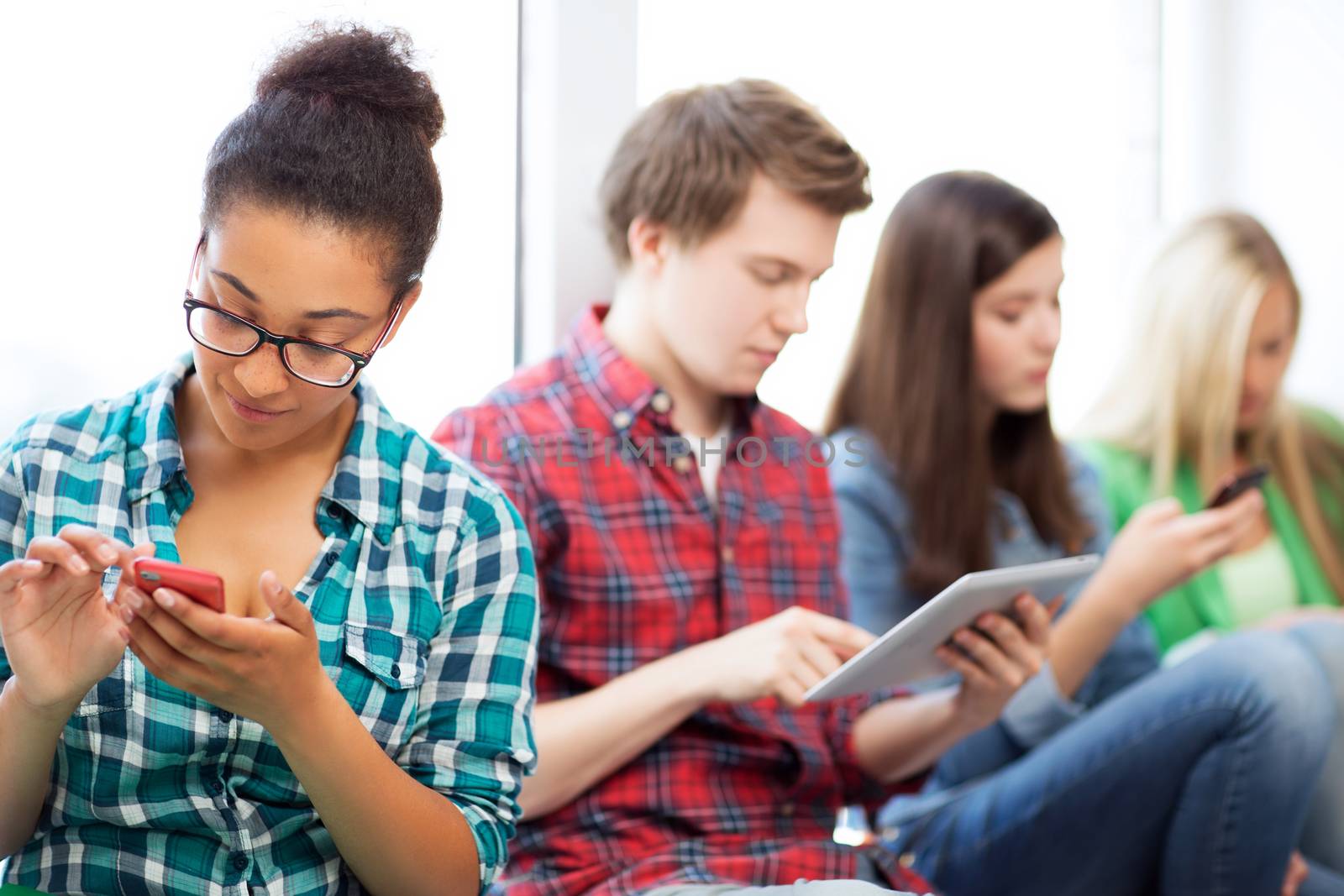 students looking into devices at school by dolgachov