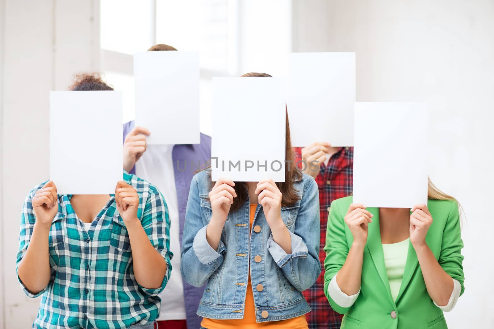 education concept - group of students covering faces with blank papers